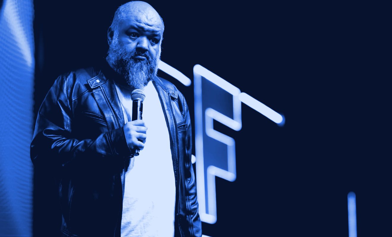 Caio Gomes falando no palco, com um microfone na mão